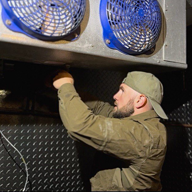 commercial refrigeration repairs 3 Technician Naz working inside a walk-in cooler, adjusting evaporator fans and refrigeration components, representing professional walkin refrigerator repair service.