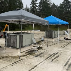 Rooftop units protected by canopies during commercial HVAC repair on a flat commercial roof.