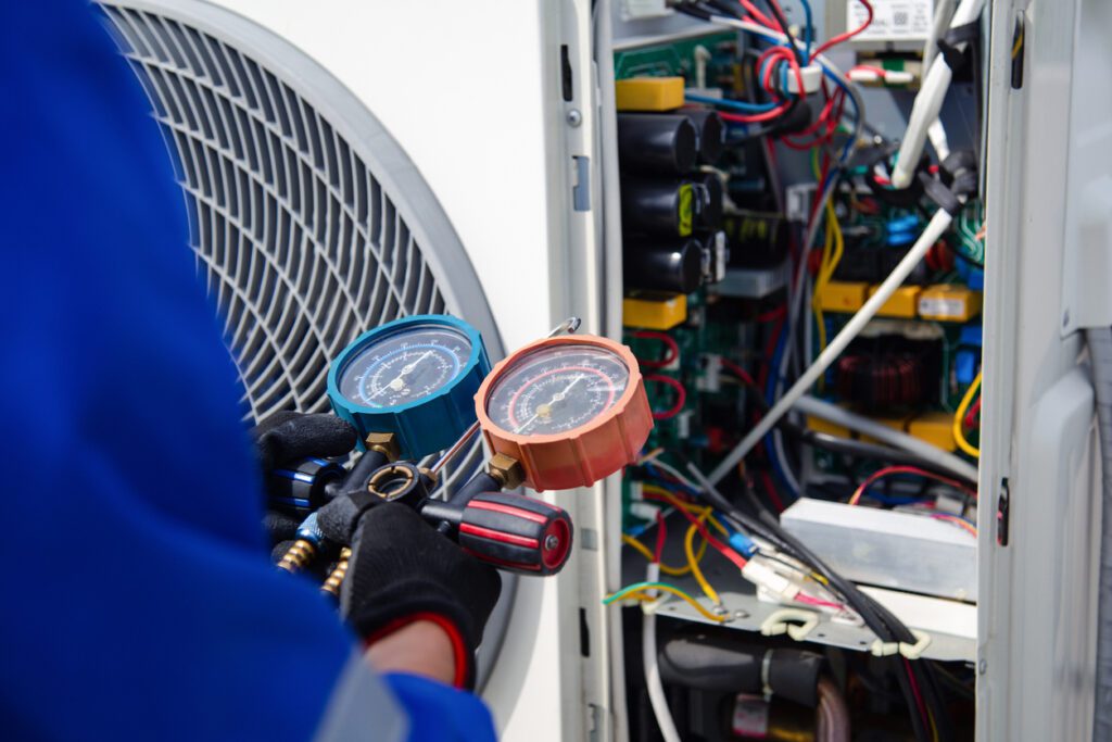 Air conditioner repairs service .The air conditioner technician is using a gauge to measure the refrigerant pressure. air compressor.