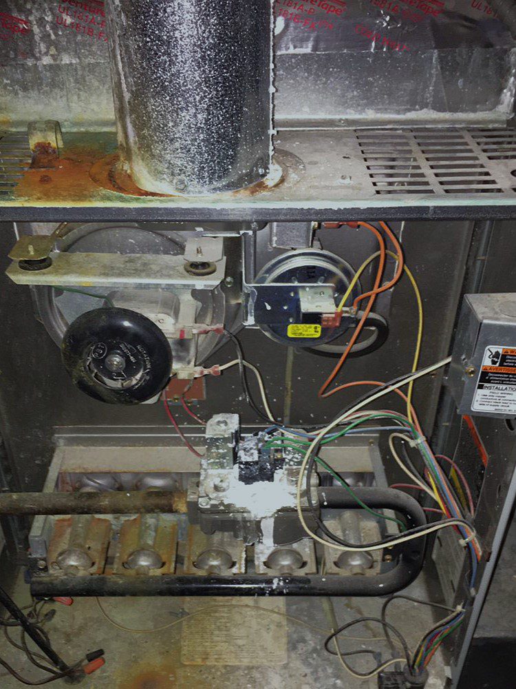 HVAC expert inspecting furnace heat exchanger for cracks and safety issues.