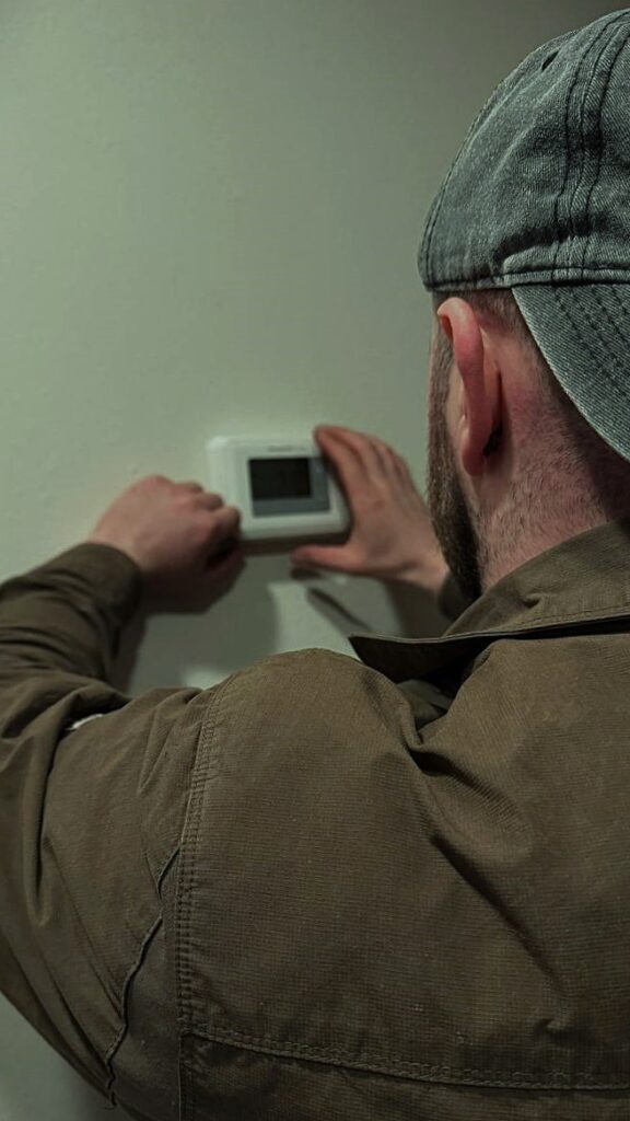 A/C Dr. Naz technician precisely installing and programming a new smart thermostat in an Everett home to optimize furnace efficiency and energy savings.