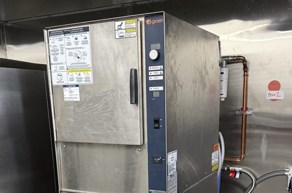 Commercial kitchen technician testing Groen steamer control board.