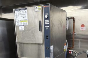 Commercial kitchen technician testing Groen steamer control board.