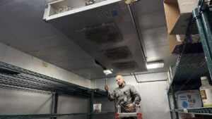 Technician checking a walk-in cooler refrigeration system for refrigerant leaks in Puget Sound