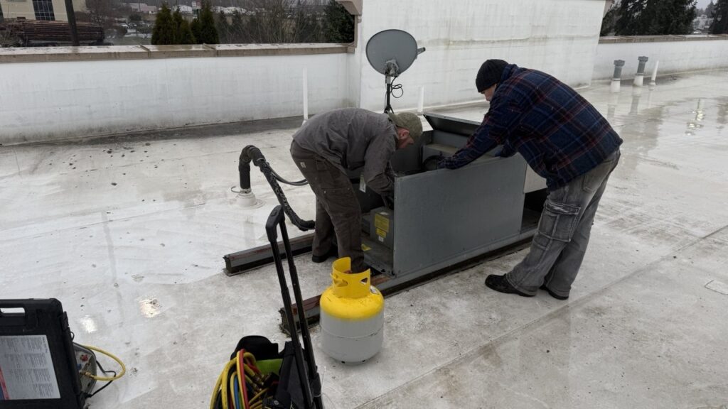 two A/C Dr. Naz Technicians are working on condenser coil repair