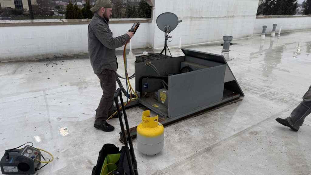 Technician is working on condenser coil repair and testing it with industry grade tool 