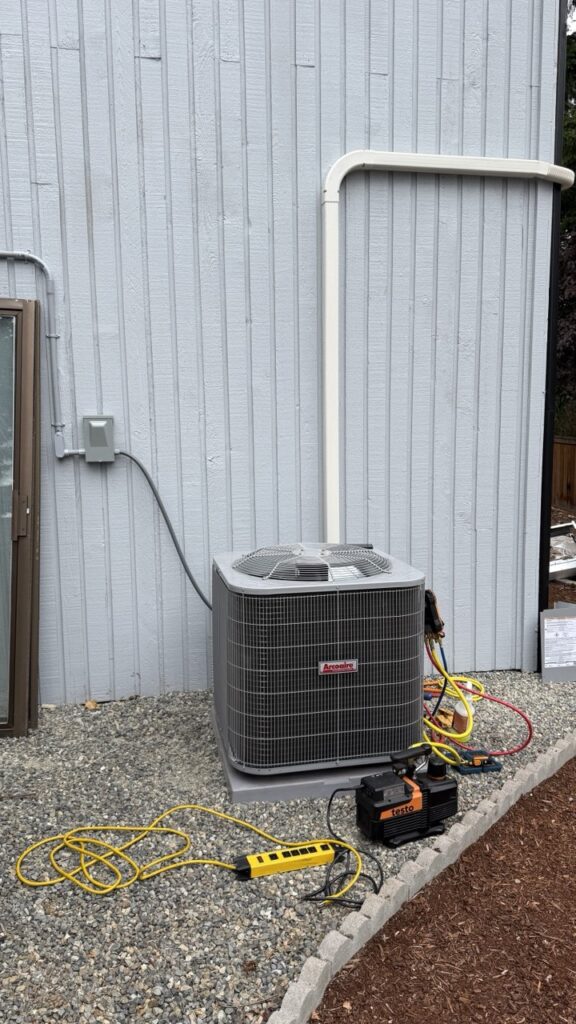 Energy-efficient outdoor heat pump unit installed in a narrow Seattle side-yard to provide hybrid heating and cooling.