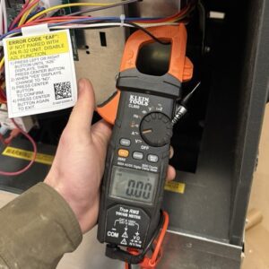 A technician is testing gas furnace with a digital clamp meter