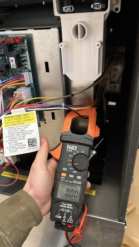 Digital multimeter testing a furnace control board for electrical faults in Seattle WA.