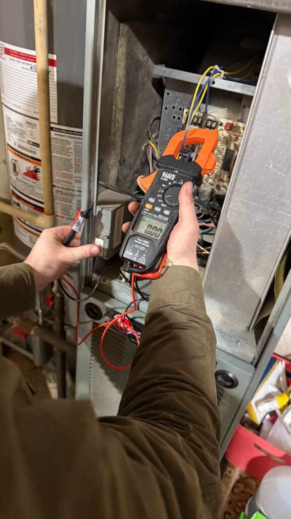 Technician testing thermostat and control system of gas furnace