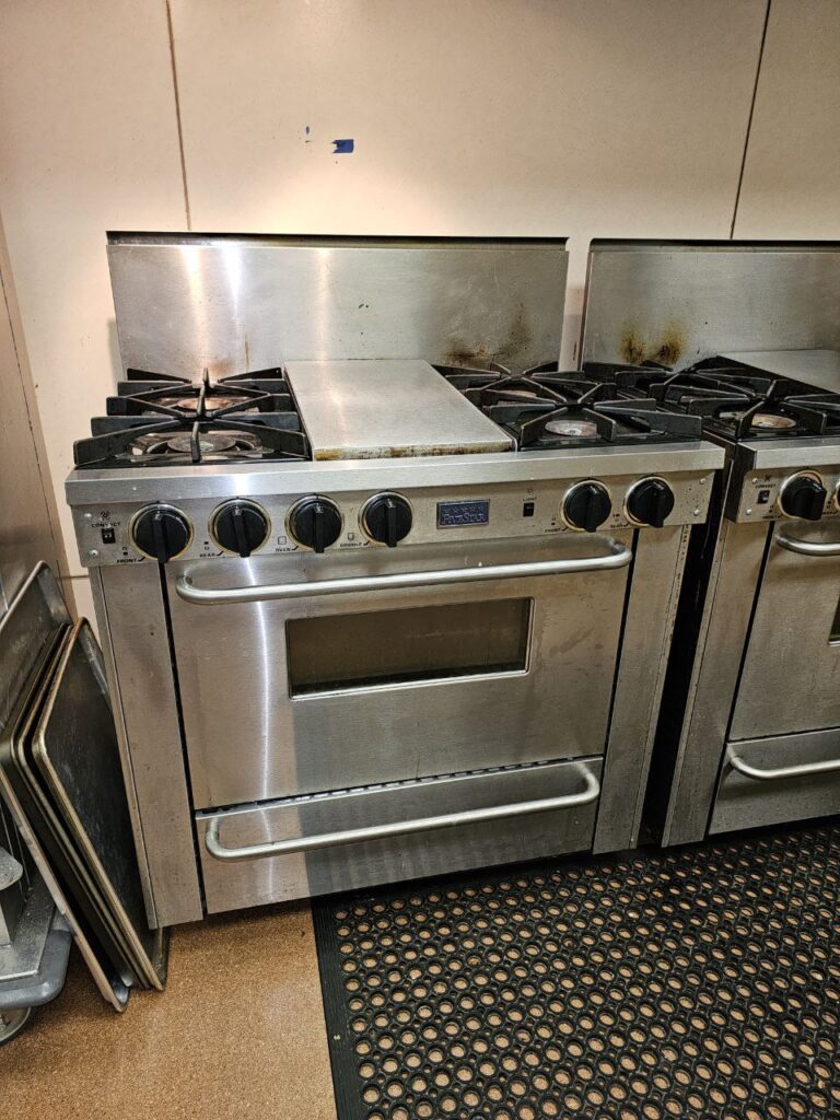 Technical view of Vulcan commercial gas range burners with heavy carbon buildup and irregular flame patterns prior to professional cleaning and adjustment in Seattle.