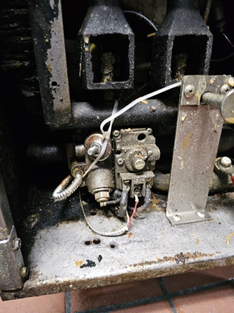 Internal view of a commercial gas range manifold and a seized heavy-duty gas control valve in a Seattle restaurant kitchen before professional disassembly and OEM part replacement.