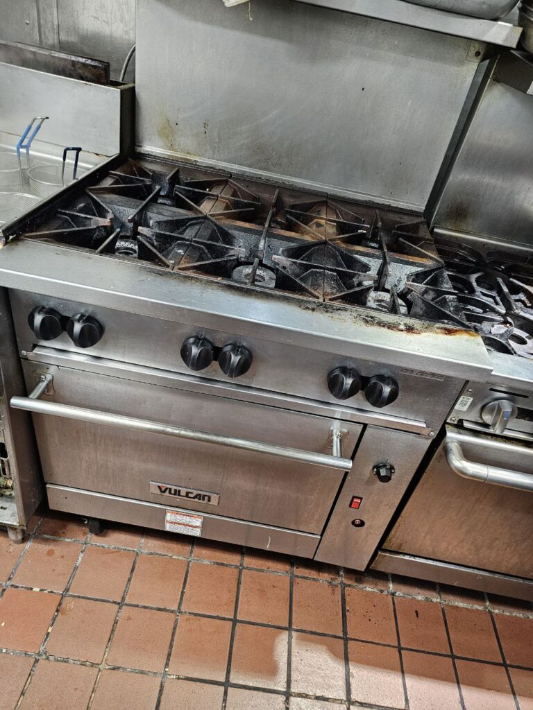 Six-burner commercial gas range in a Seattle restaurant kitchen awaiting diagnostic inspection for ignition failure before repair work starts.