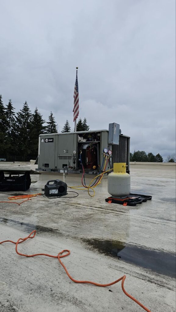 A/C Dr. Naz technician performing diagnostic testing on a Trane rooftop HVAC unit during a commercial maintenance call in Seattle, WA.