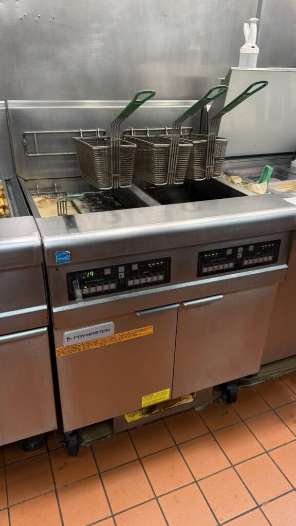 A professional Frymaster commercial fryer with a digital control panel and ENERGY STAR® certification, shown with baskets hanging during a routine maintenance check in a Seattle kitchen.