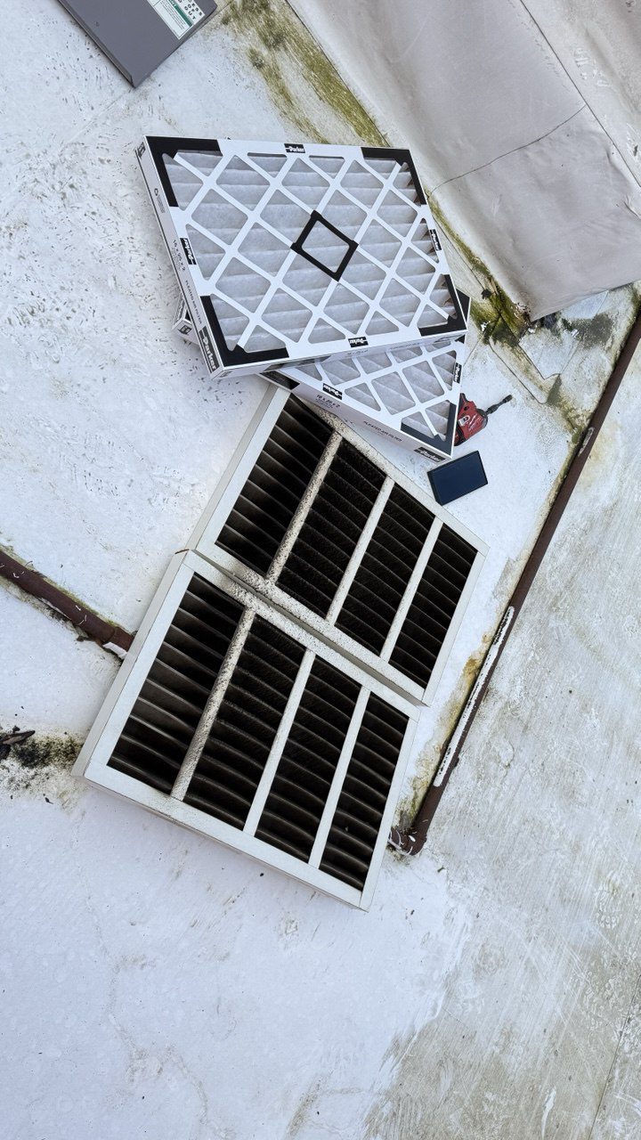 Technician replacing dirty air filters with high-efficiency Parker pleated filters in a commercial HVAC system in Seattle.
