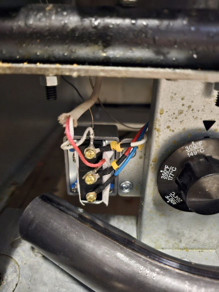 Detailed view of the electrical terminal block for a commercial fryer's thermostat, showing color-coded wiring (blue, red, and white) and spade connectors attached to the temperature control unit.