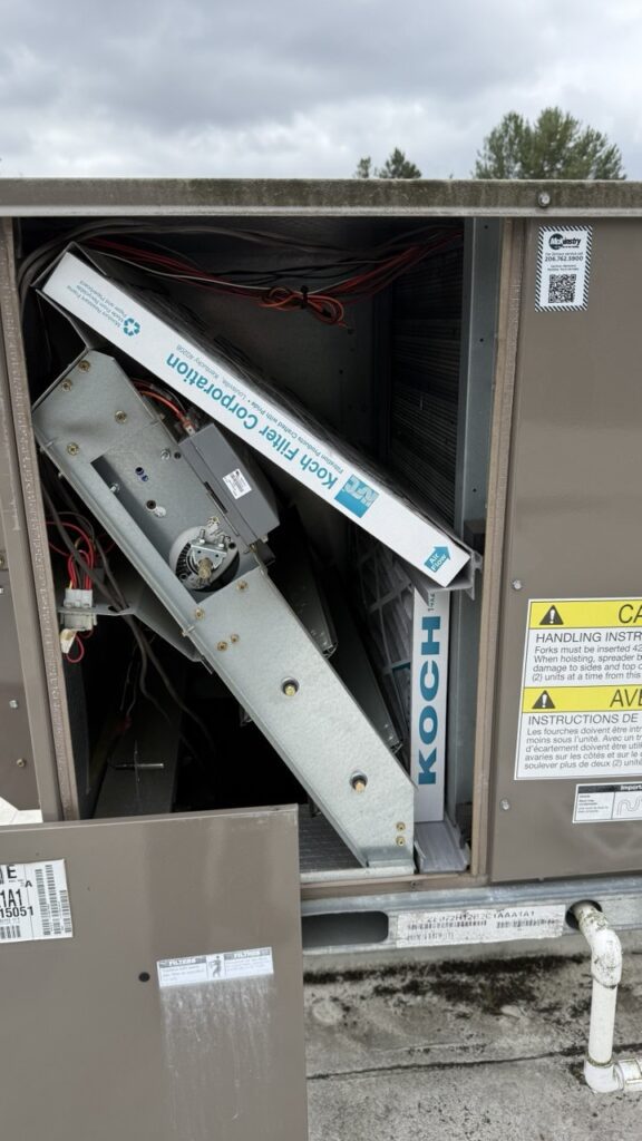 Installing new Koch high-efficiency air filters into a commercial rooftop HVAC cabinet as part of a Seattle maintenance plan.