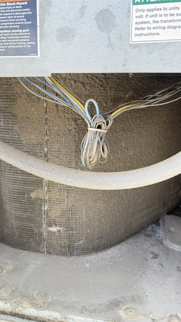 Detailed inspection of internal wiring and debris buildup on a commercial HVAC unit's condenser coils.