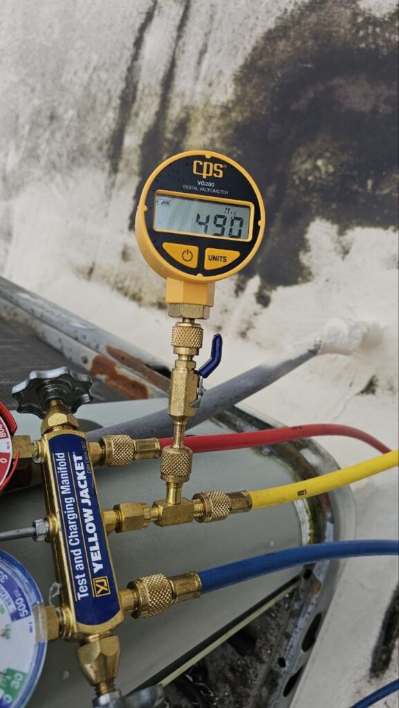 A/C Dr. Naz using a CPS digital micron gauge and Yellow Jacket manifold to perform a deep vacuum pull on a commercial HVAC system, reaching 490 microns for a moisture-free refrigeration circuit.