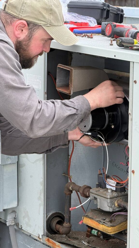 Commercial HVAC technician inspecting 3-phase contactor and compressor system on commercial AC unit