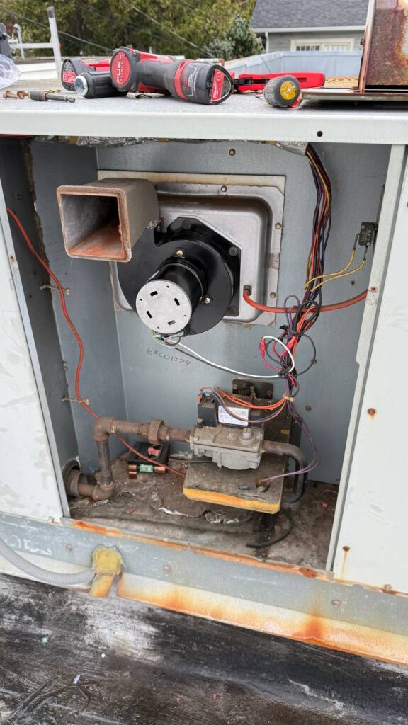 Disassembled rooftop unit showing inducer motor assembly and internal HVAC components