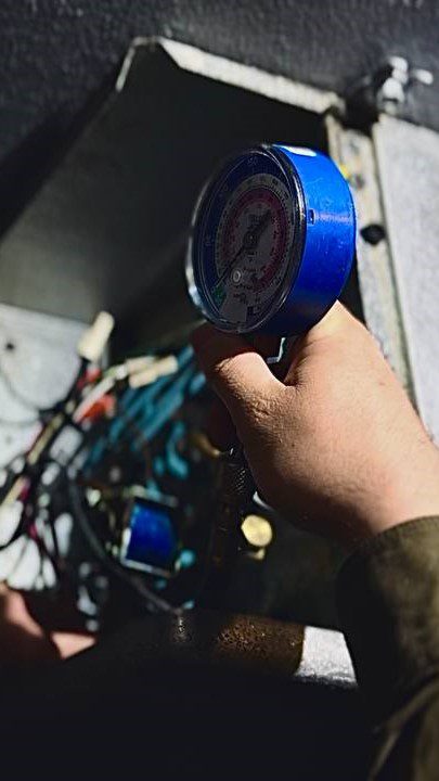 A/C Dr. Naz technician performing on-site walk-in freezer work—verifying refrigerant-side readings, safeties, and defrost behavior on commercial low-temp equipment.