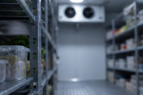 Walk‑in cooler interior with blurred shelving, illustrating refrigeration recovery issues during busy shifts.