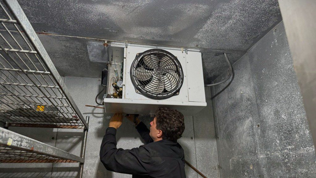 A/C Dr. Naz technician repairing a commercial walk-in cooler evaporator