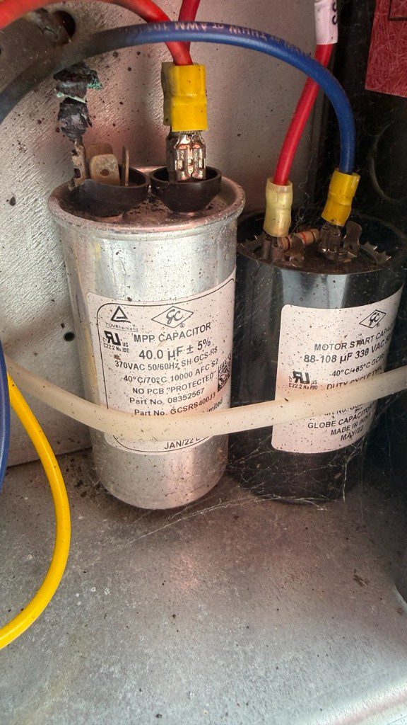 Damaged motor start and run capacitors in a commercial refrigeration electrical box
