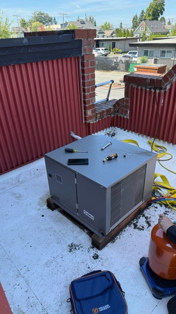 Refrigerant tank on a digital scale with manifold hoses connected to a rooftop condensing unit