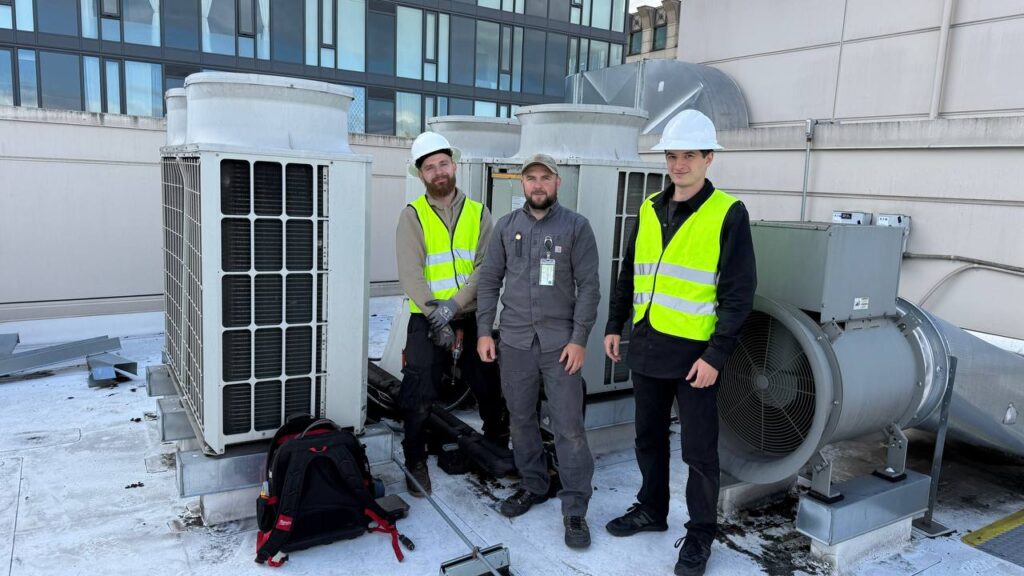 A/C Dr. Naz technicians on a commercial rooftop beside the units they service