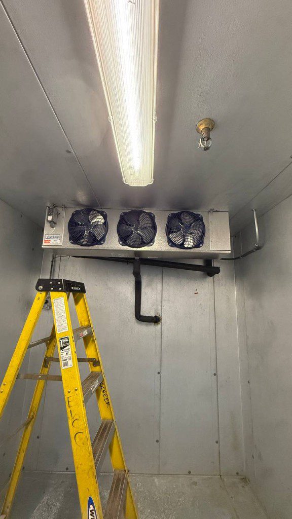 Field photo of three-fan walk-in evaporator with ladder during service — serves Granite Falls, WA commercial refrigeration repair