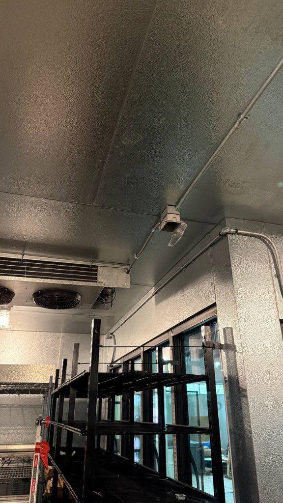 Field photo of walk-in cooler interior showing evaporator and electrical conduit — serves Sammamish, WA commercial refrigeration repair