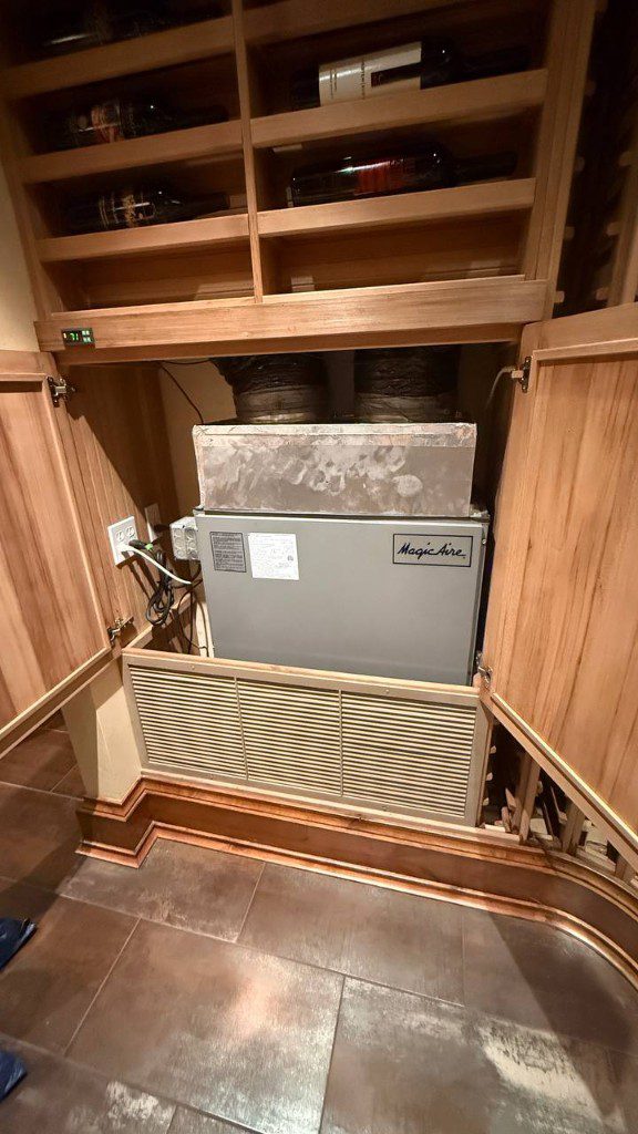Field photo of wine cellar cooling unit installed inside wood cabinetry — serves Issaquah, WA commercial refrigeration repair
