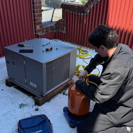 Technician servicing rooftop refrigeration